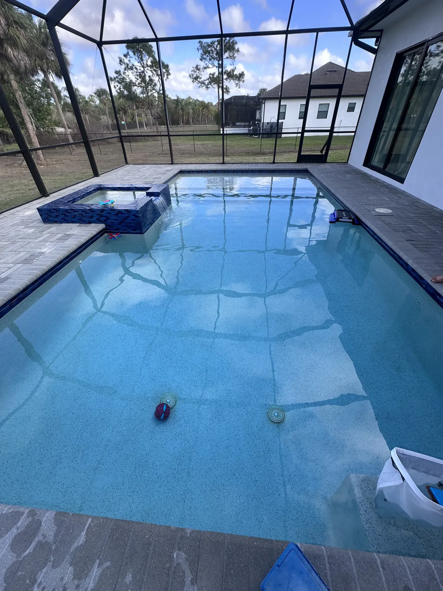 Screened pool enclosure with cleaning tools ready at the water's edge